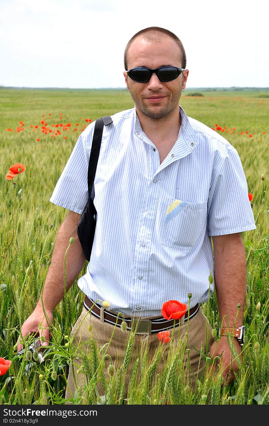 A young man with glasses standing in a field of wheat. A young man with glasses standing in a field of wheat