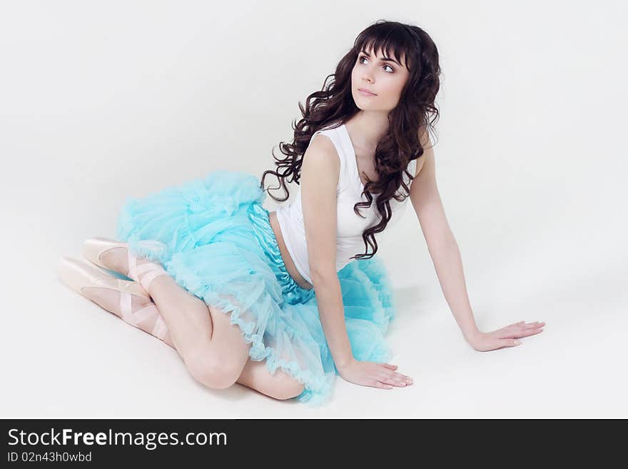 Beautiful girl the ballerina sits on a floor