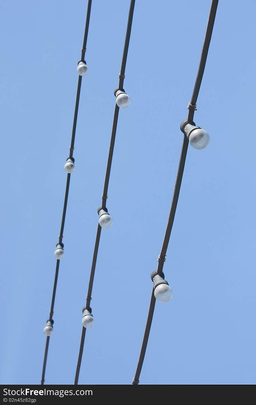 Garland wires with three glow lamps in the blue sky. Garland wires with three glow lamps in the blue sky