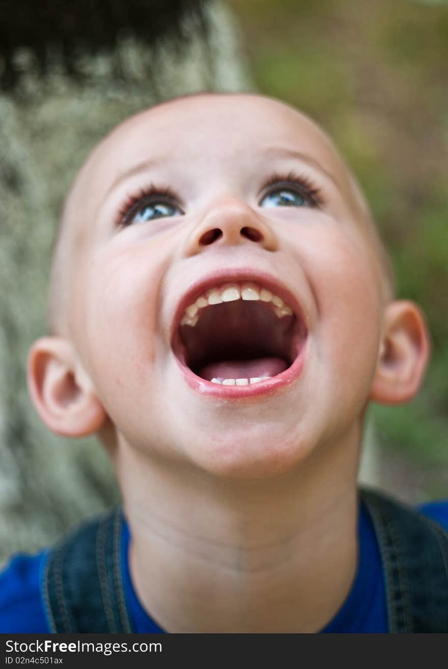 A boy screams happily while his head is thrown back. A boy screams happily while his head is thrown back