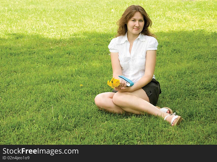 Atrractive woman is sitting on grass with book. Atrractive woman is sitting on grass with book