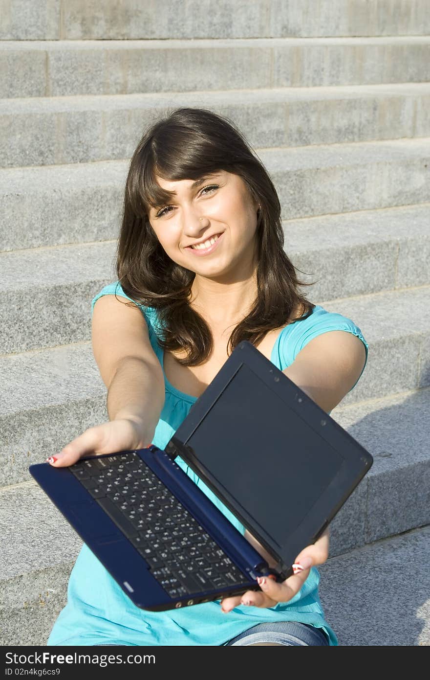 Woman outdoors sitting on the steps the school with a laptop. Notebook in hand stretched out in the frame. Woman outdoors sitting on the steps the school with a laptop. Notebook in hand stretched out in the frame