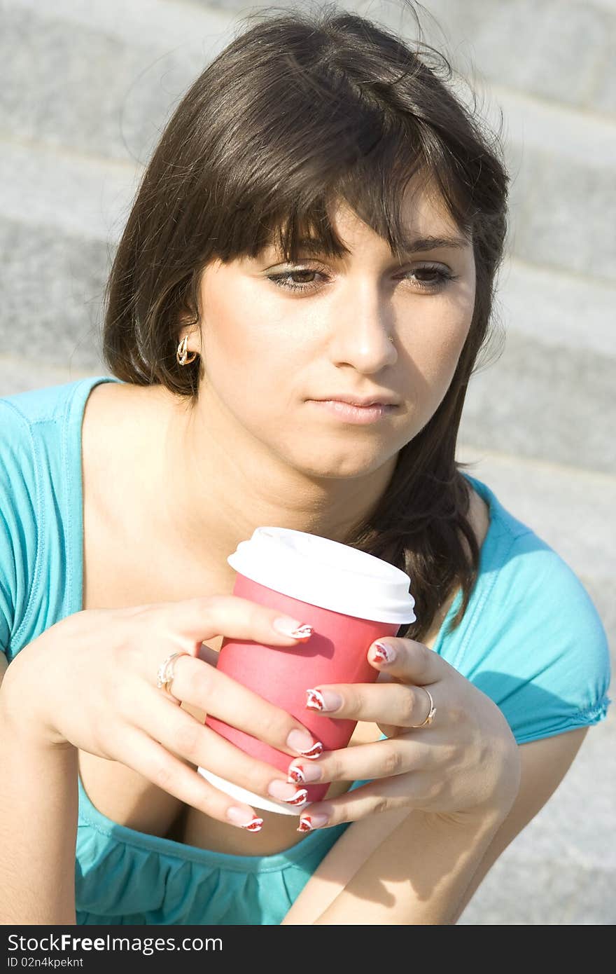 A beautiful young woman relaxing. Drinking coffee from paper cups. Portrait. A beautiful young woman relaxing. Drinking coffee from paper cups. Portrait