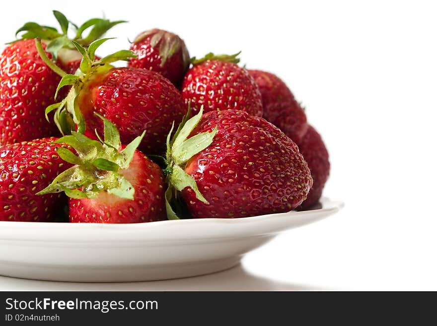 Ripe strawberry on a dish, with a shade, on a white background