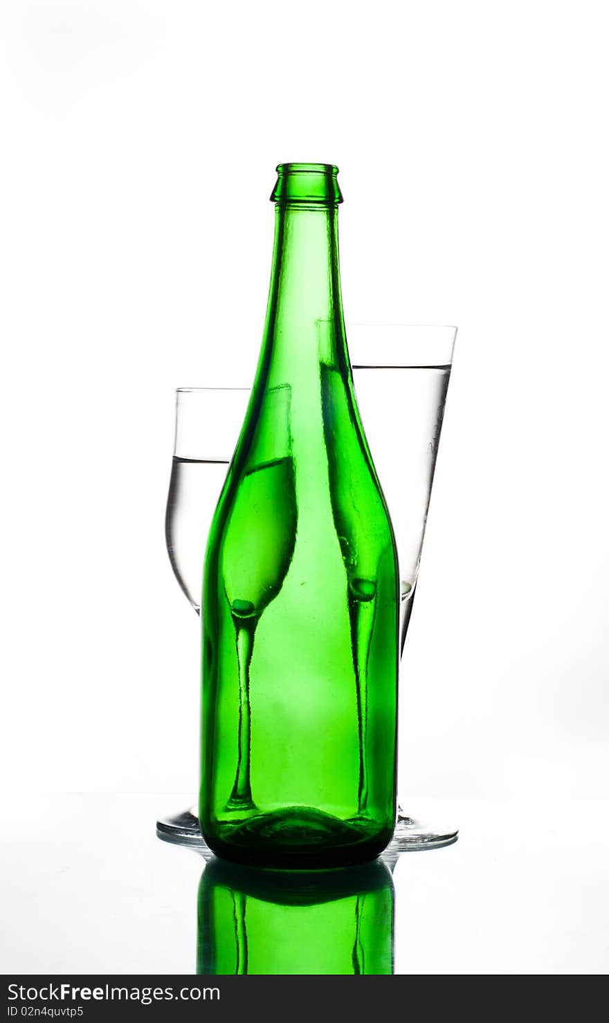 Green bottle and two glasses on glass table water