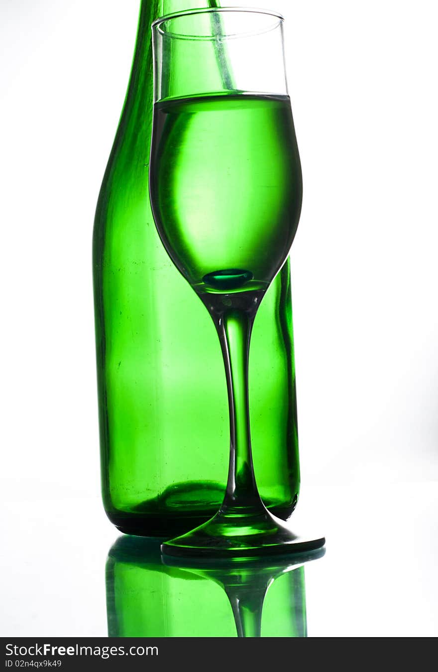 Green bottle and glasses on glass table water