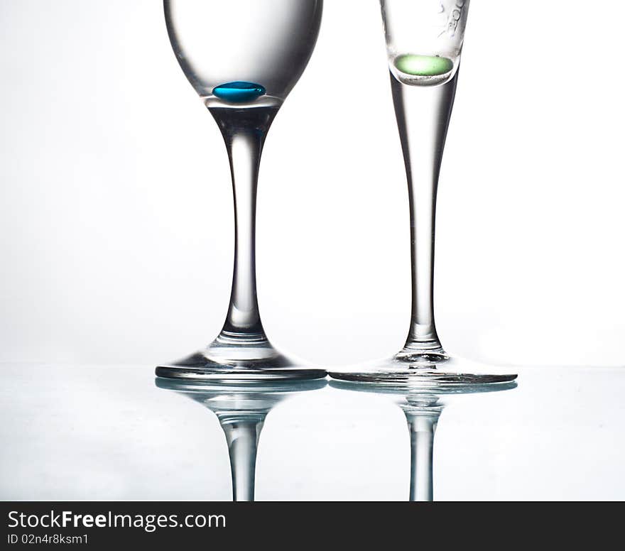 Two glasses on the glass table with colorful pills water. Two glasses on the glass table with colorful pills water