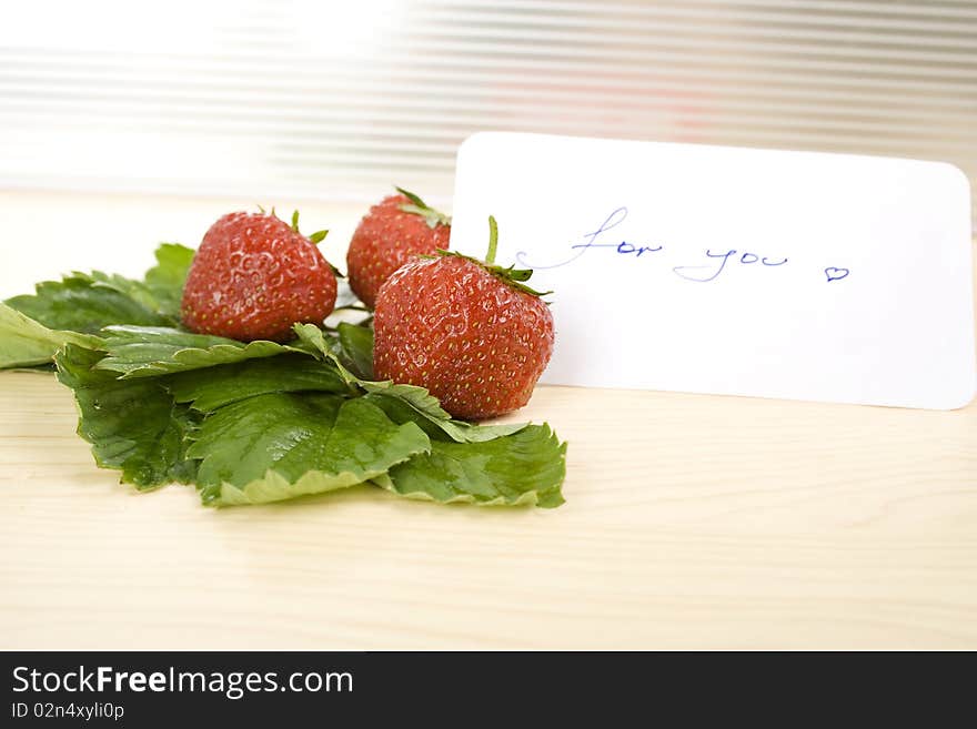 Juicy red strawberries and green leaves on the table next card is the text for you. Juicy red strawberries and green leaves on the table next card is the text for you