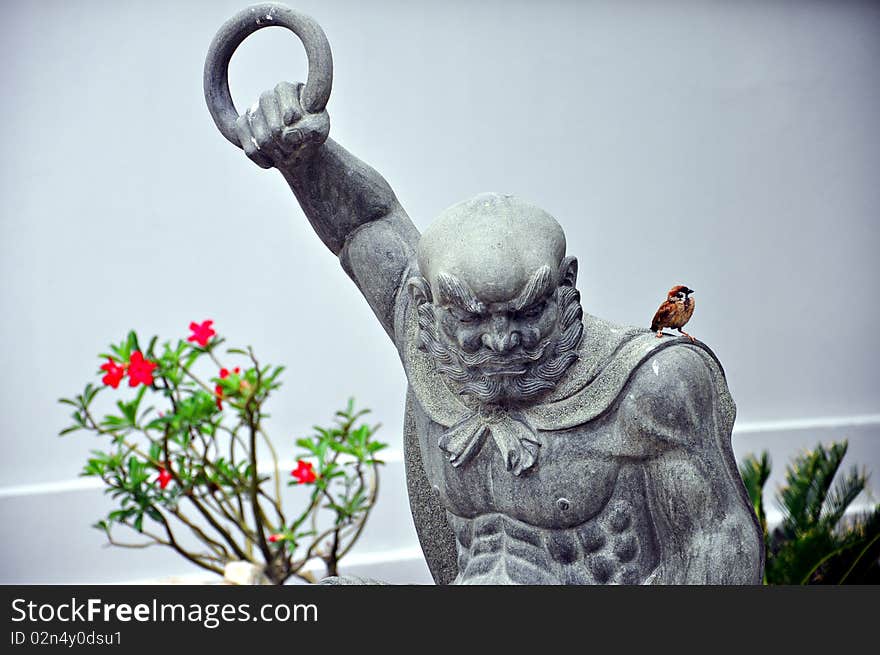 Fierce Chinese warrior statue and a little bird. Fierce Chinese warrior statue and a little bird