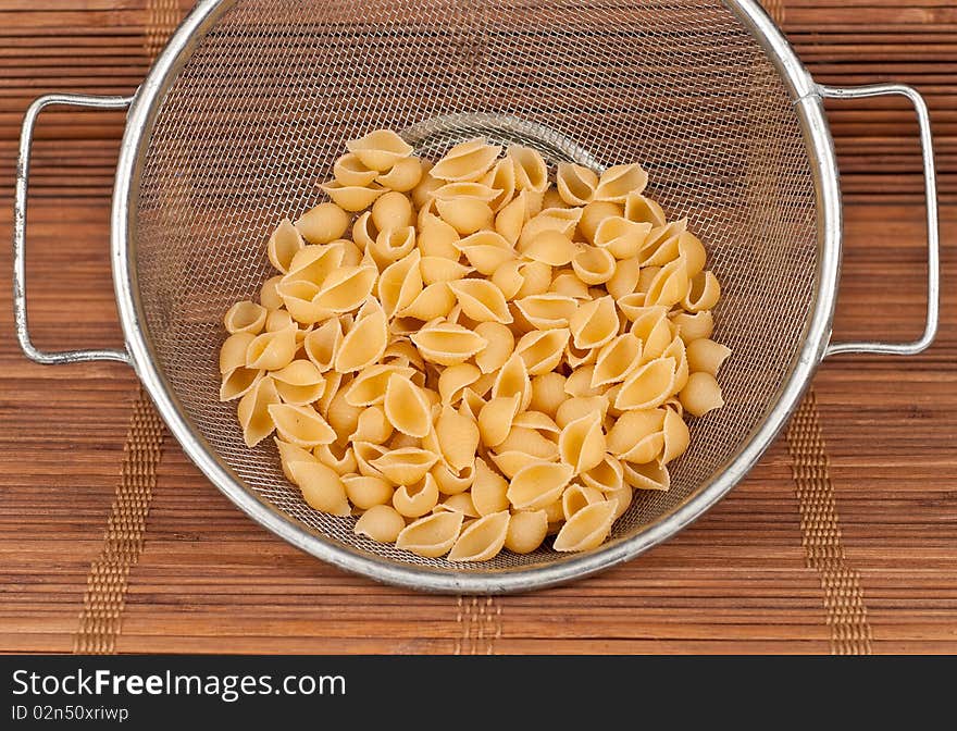 Dry Pasta in Strainer on Bamboo Mat