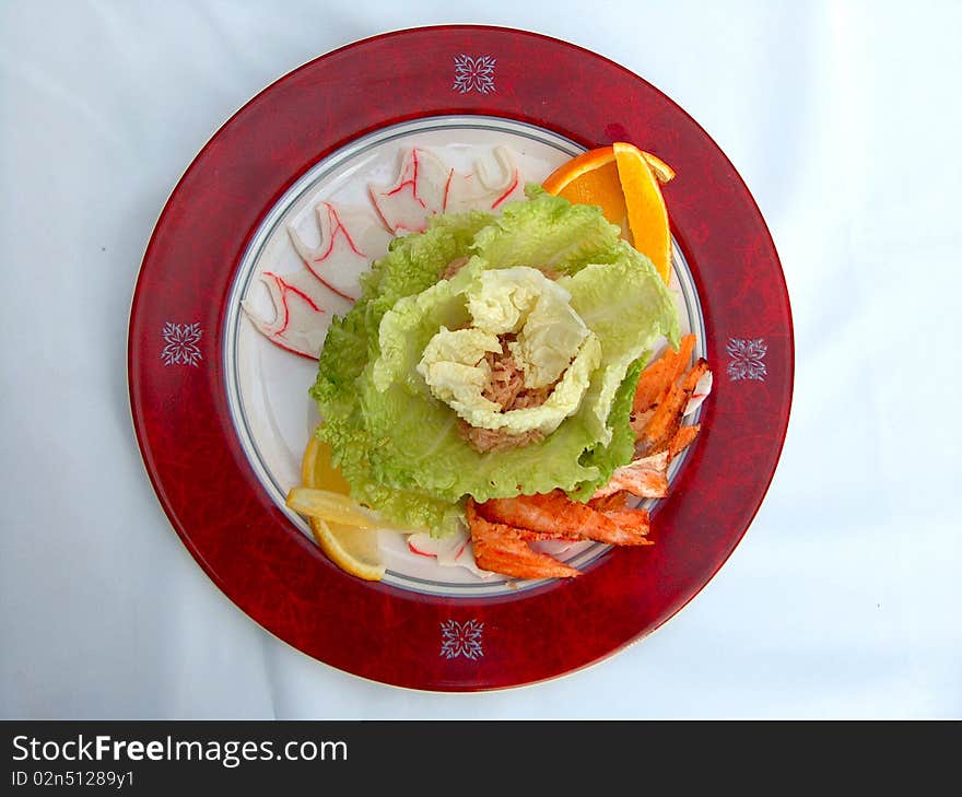 The red plate of Tunas salad. Components: the Chinese salad, crab meat, shrimps, an apple, a dark blue onions, a tuna and mayonnaise.