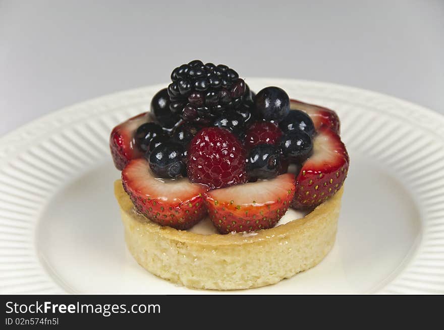 Delicious mixed berry patisserie tart. Red, white and blue holiday celebration theme. Soft focus, close-up. Delicious mixed berry patisserie tart. Red, white and blue holiday celebration theme. Soft focus, close-up.