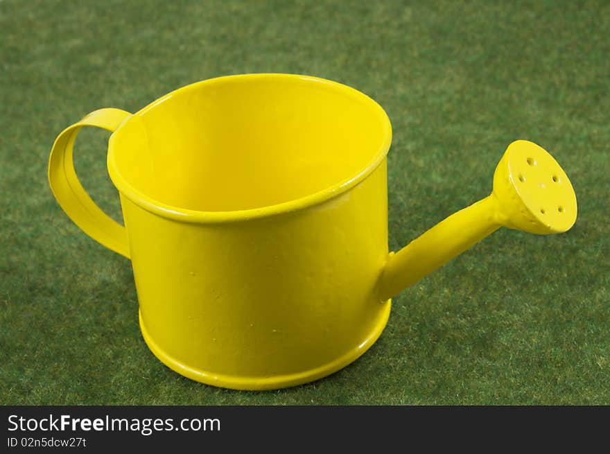 Yellow watering can on a green grass carpet