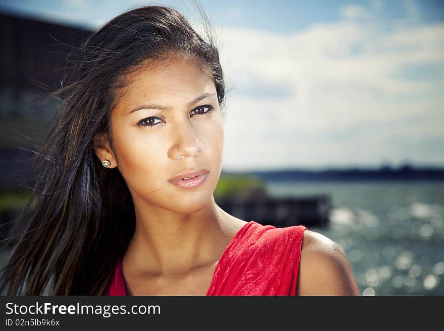 Young hispanic female by the water in red dress. Young hispanic female by the water in red dress