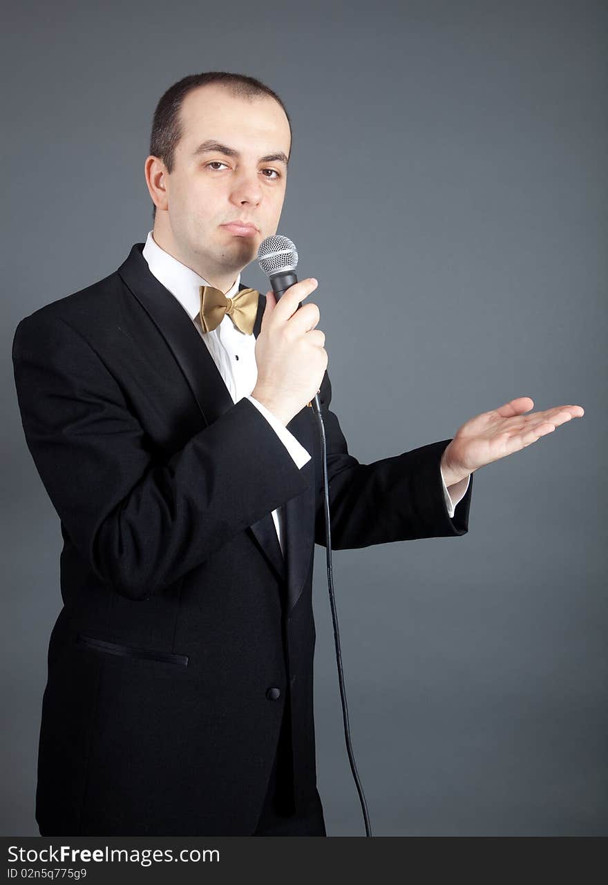 Man in tuxedo talks into microphone. Man in tuxedo talks into microphone