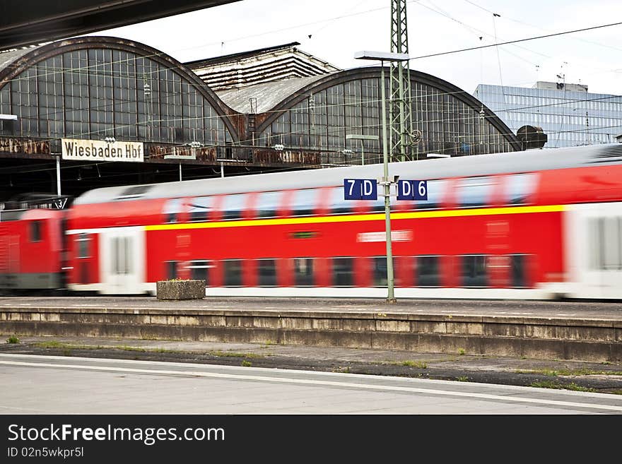 Red train in classicistic iron train stationwith speed