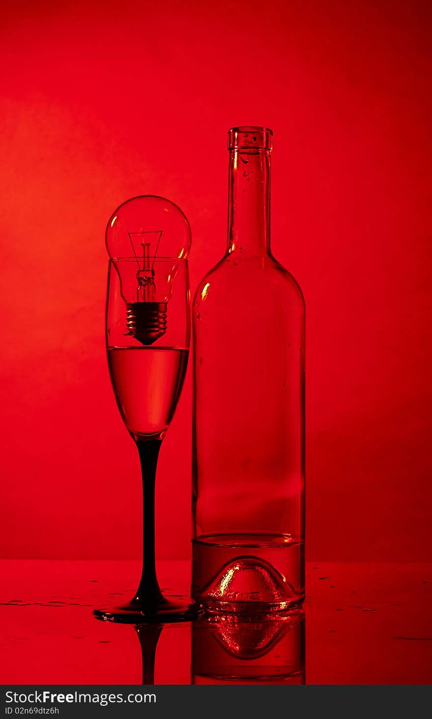 Bottle, glass and bulb on red background