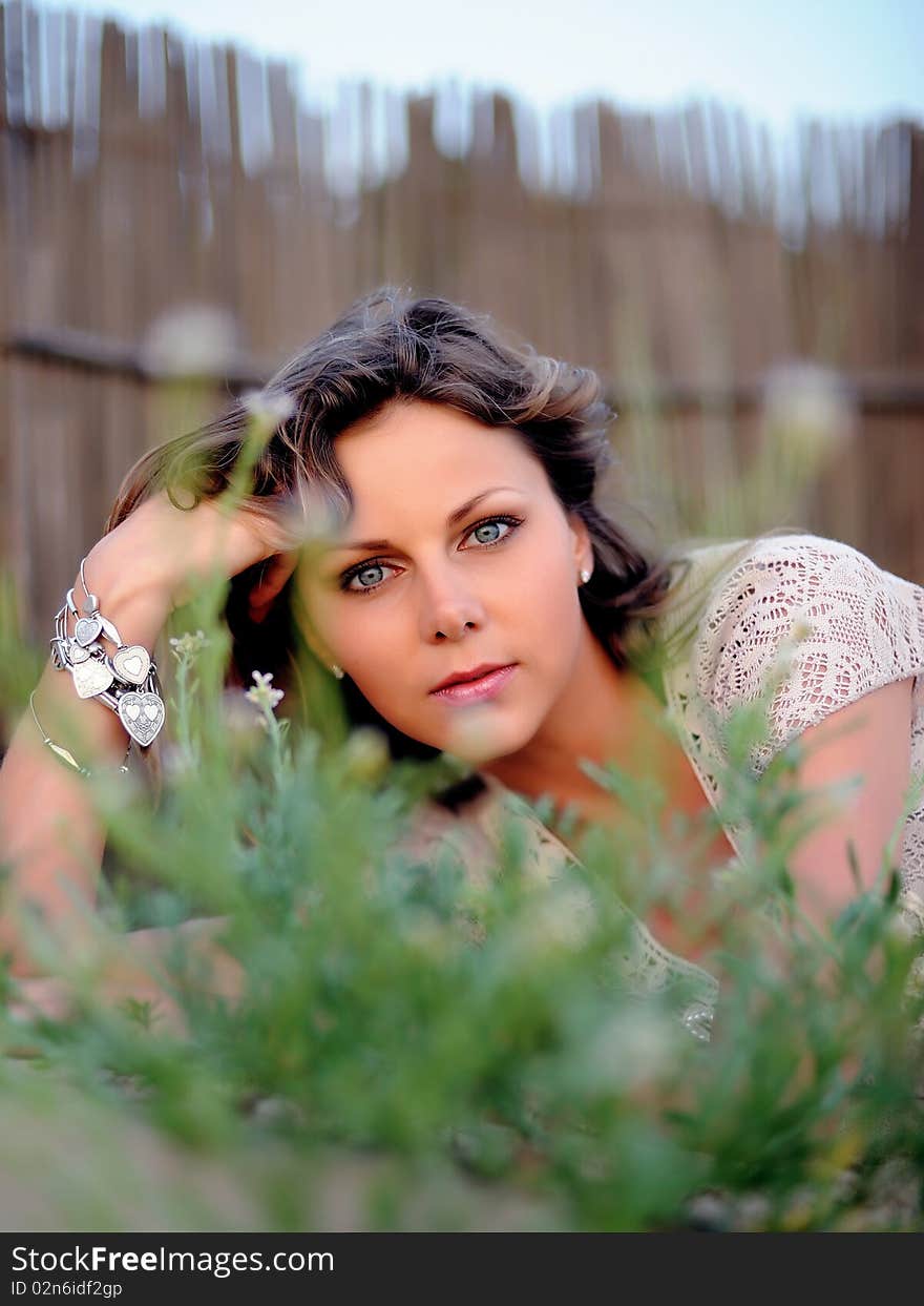 Young pretty summer woman lying on the grass and smiling