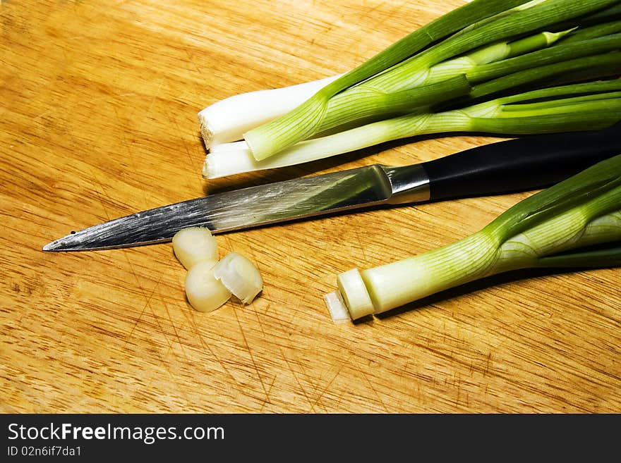 The wooden chopping board (for to cut of products of a feed) on which lays a knife and onions, which have begun to cut. The wooden chopping board (for to cut of products of a feed) on which lays a knife and onions, which have begun to cut