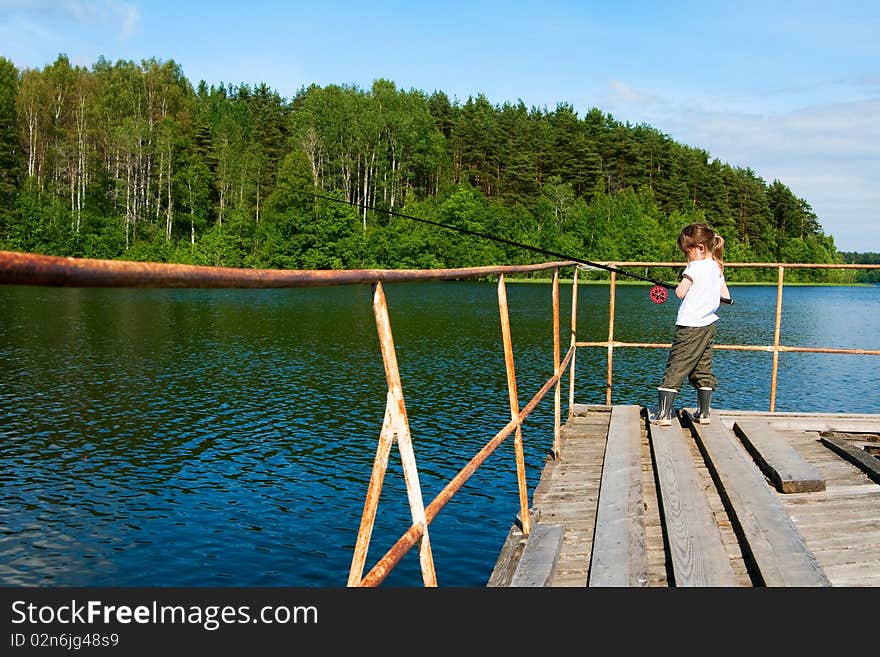 Little beautifull girl fishing. She stays on old pier with long rod. Little beautifull girl fishing. She stays on old pier with long rod.