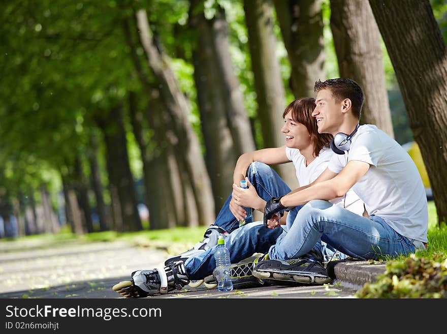 Two young guys on rollers sit on a border. Two young guys on rollers sit on a border