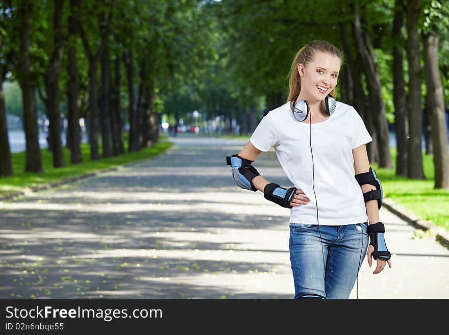 The young attractive girl with ear-phones in park. The young attractive girl with ear-phones in park