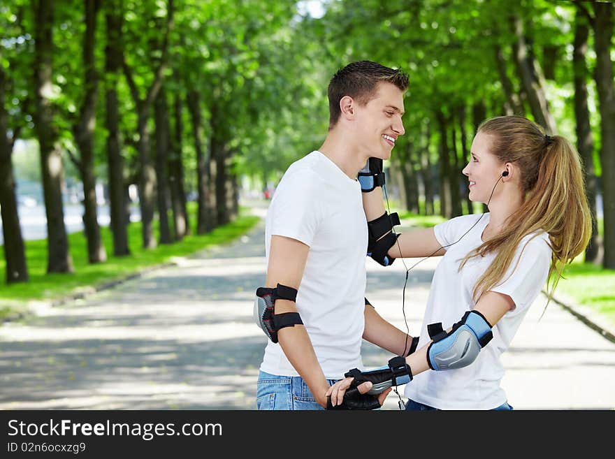 The girl in park gives an ear-phone to the man. The girl in park gives an ear-phone to the man