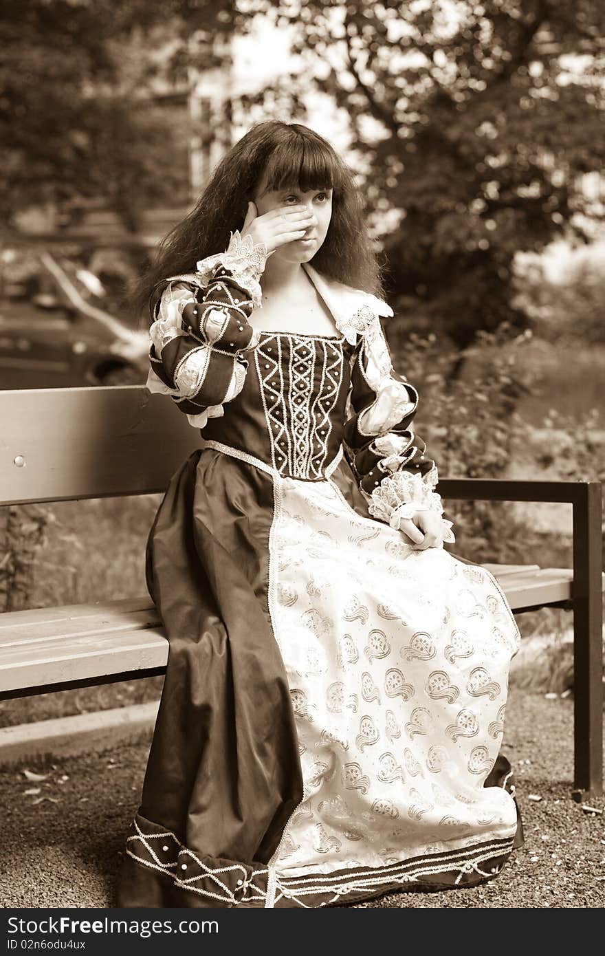 A girl in medieval dress sitting on a bench. A girl in medieval dress sitting on a bench