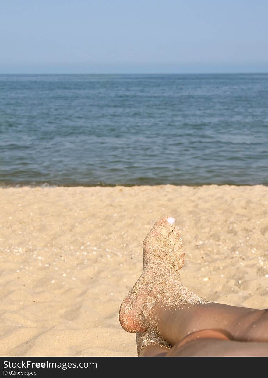 Two women feet on the calm and sunny, empty beach. Two women feet on the calm and sunny, empty beach.