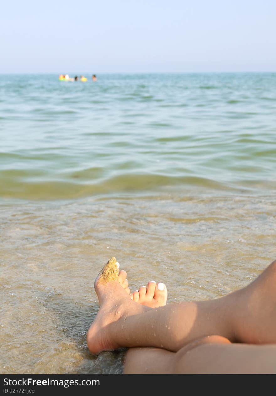 Two women feet on the calm and sunny, empty beach. Two women feet on the calm and sunny, empty beach.