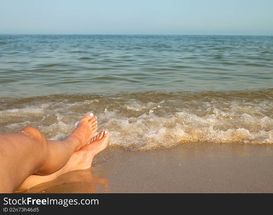 Two women feet on the calm and sunny, empty beach. Two women feet on the calm and sunny, empty beach.