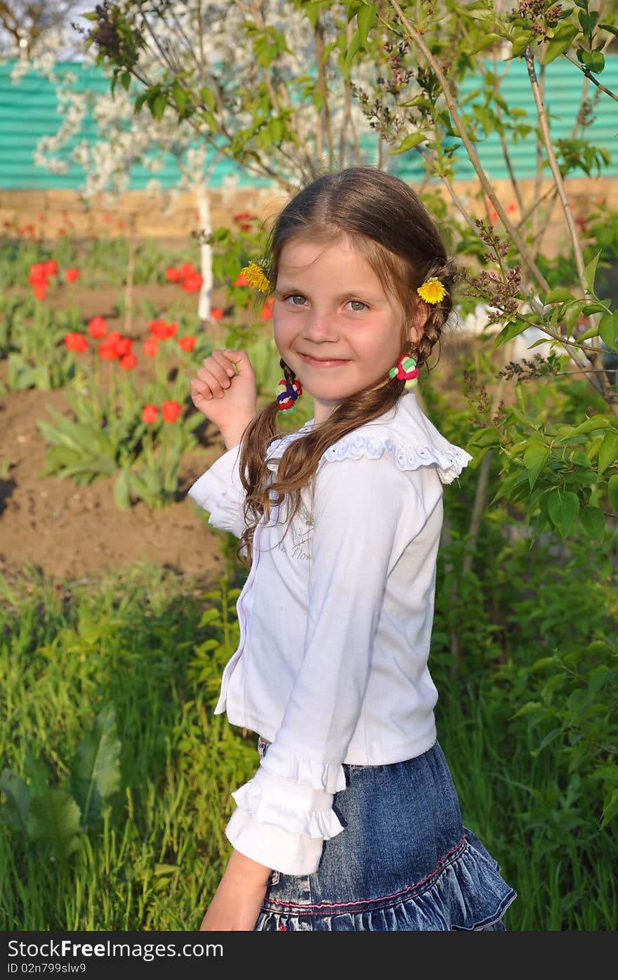 Little girl stands and smiles in the spring garden. Little girl stands and smiles in the spring garden