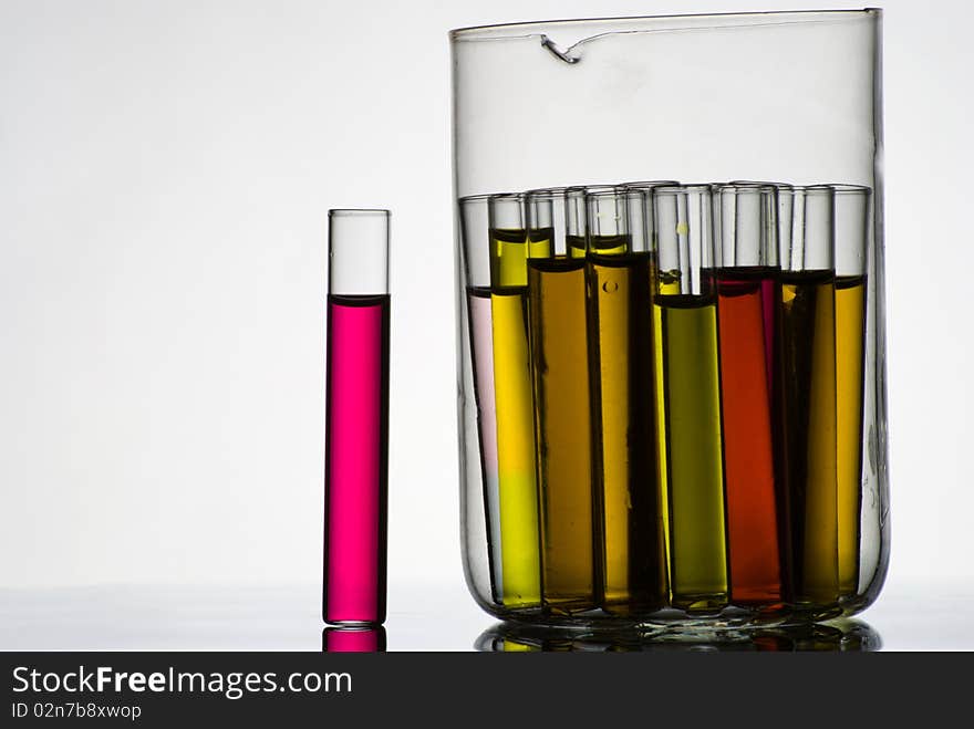 Test tubes filled with colored liquids in glass container on white. Test tubes filled with colored liquids in glass container on white