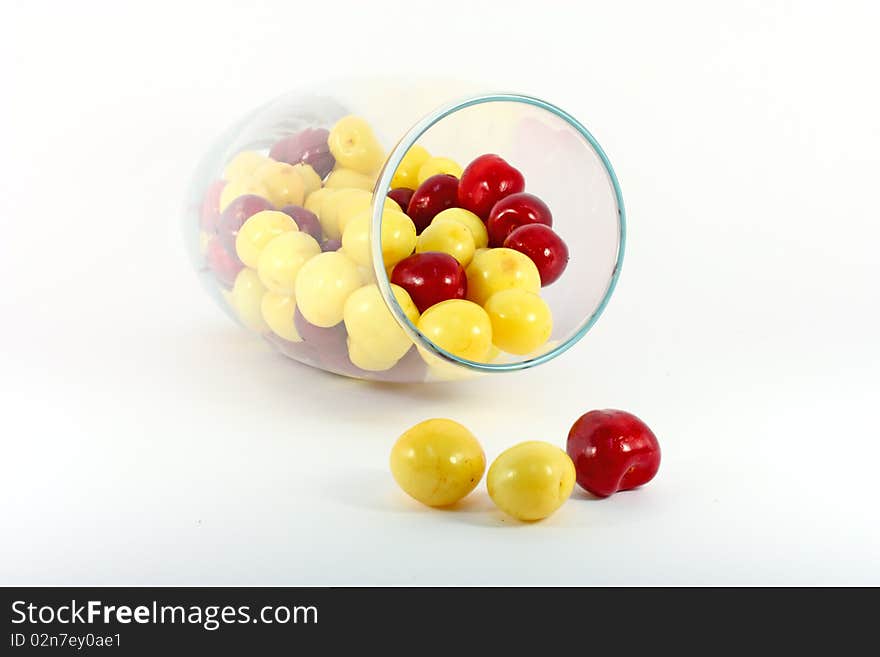 Red and yellow cherries in glass isolated on white