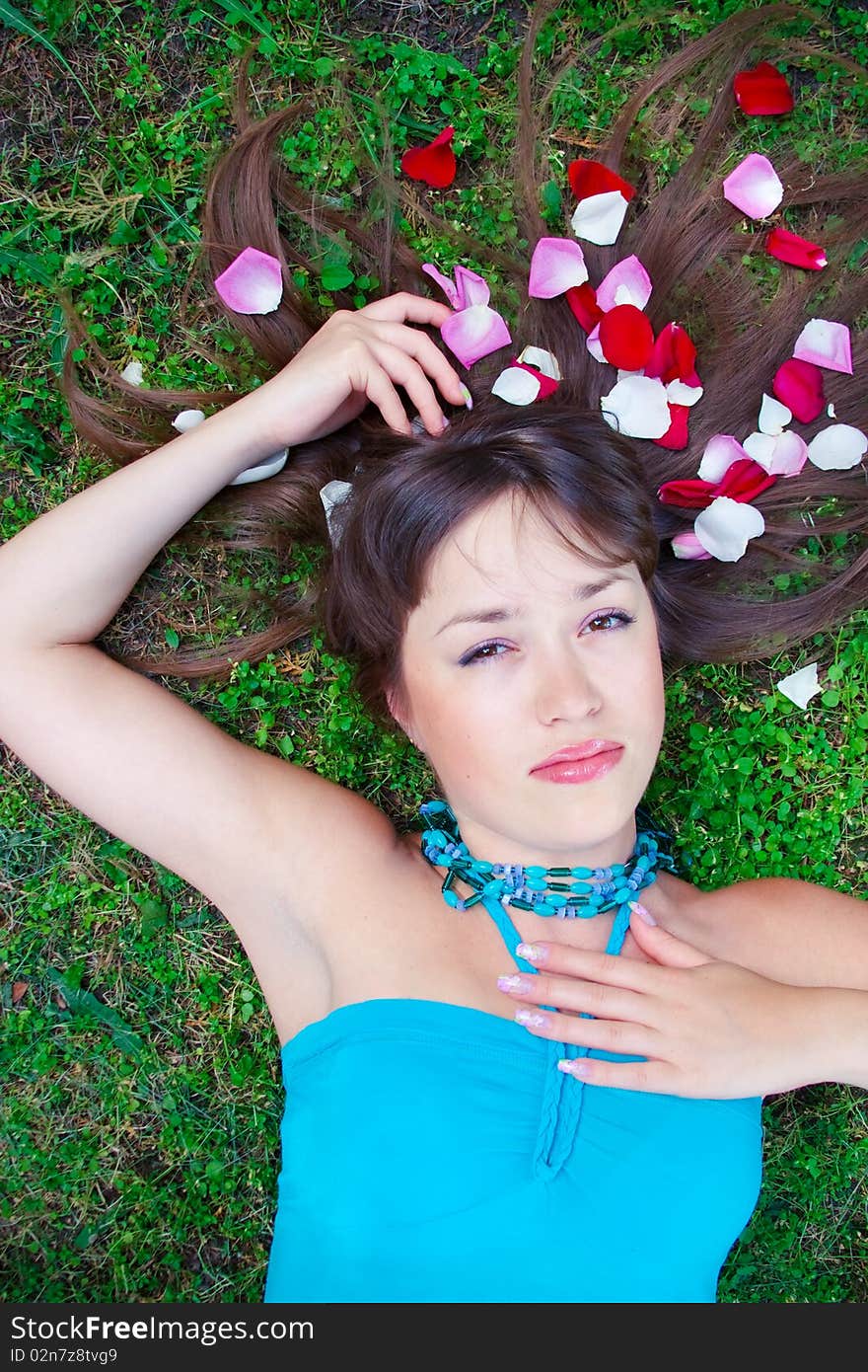 Girl is laying on the grass with petals in hair