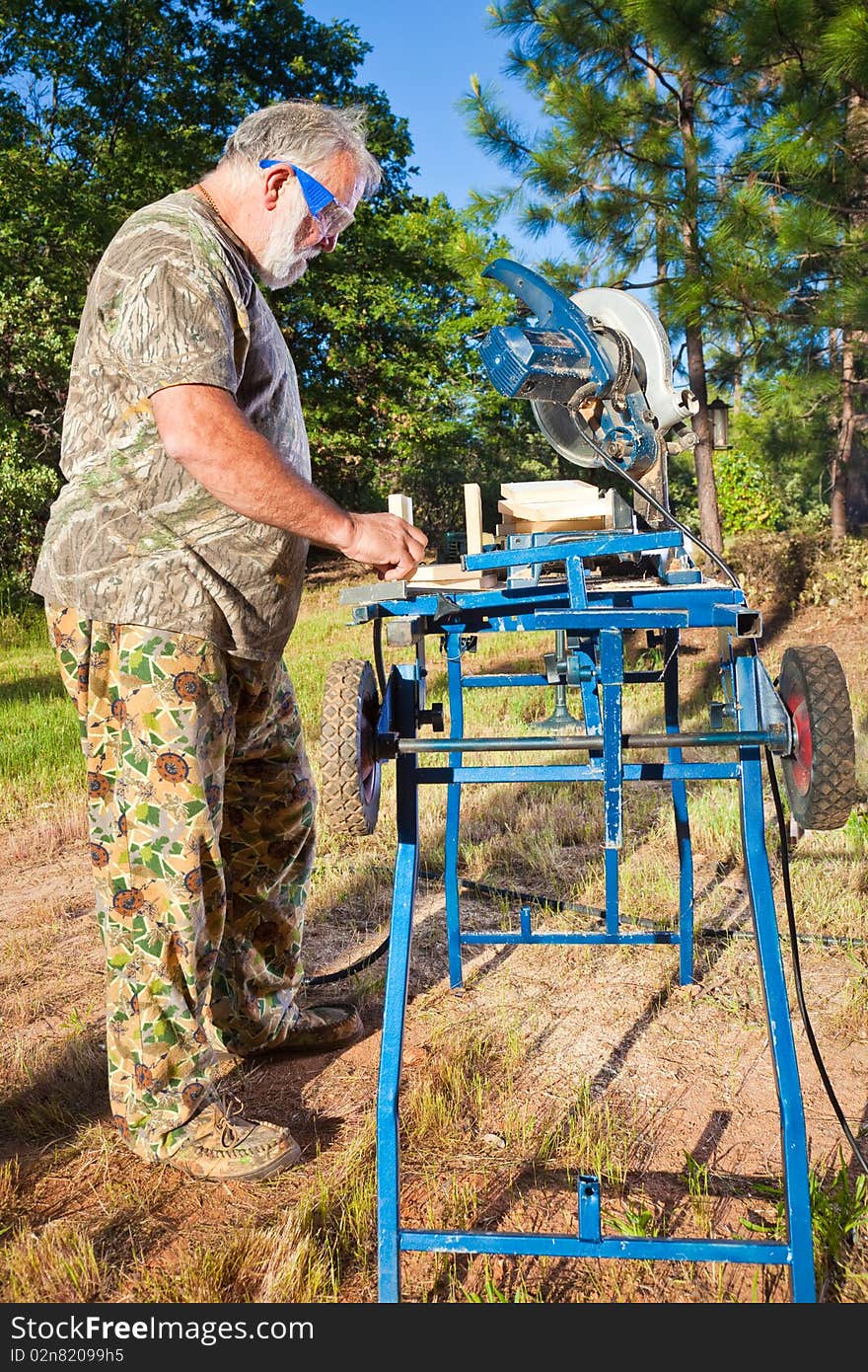 Active older man working with wood in the yard. Active older man working with wood in the yard.