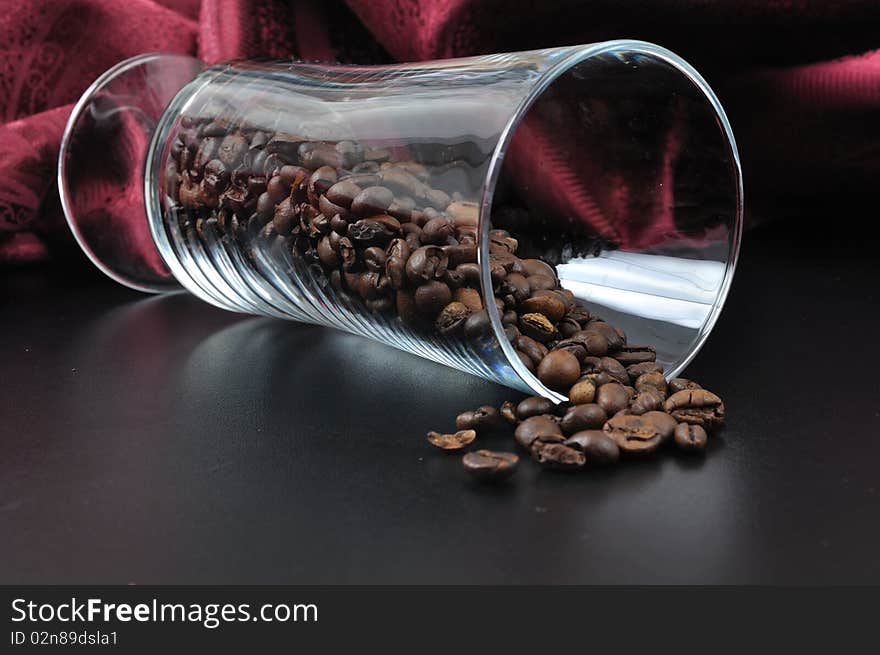 Pure glass with coffee granules on black table with red samet background