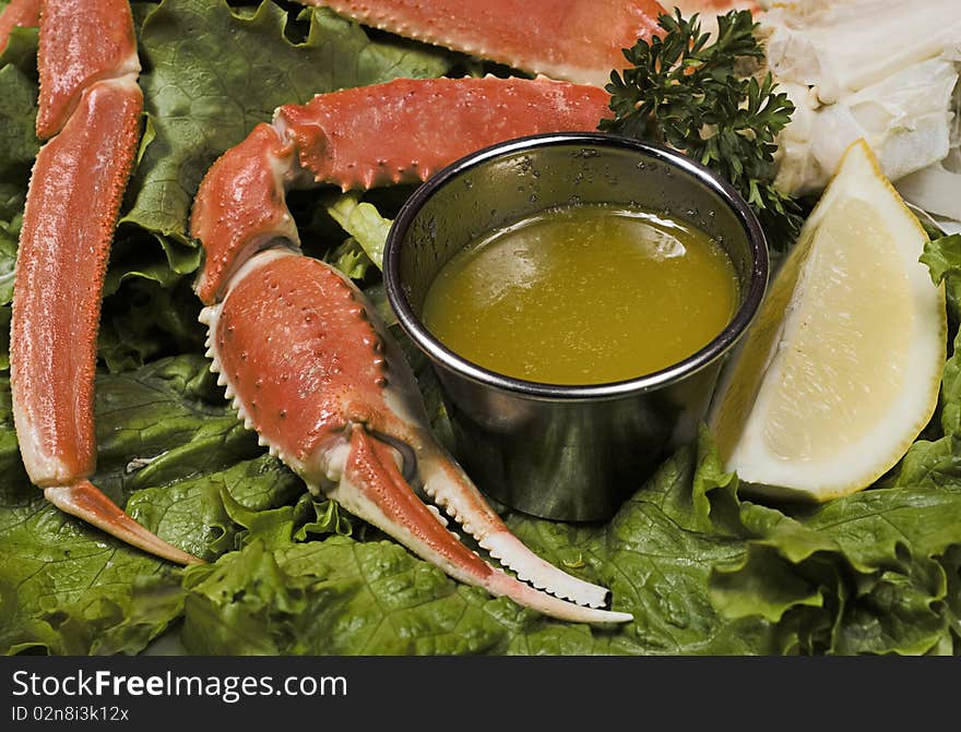 A red crab pinch from a close up view with melted butter on the side in a cup and a slice of fresh lemon. A red crab pinch from a close up view with melted butter on the side in a cup and a slice of fresh lemon.