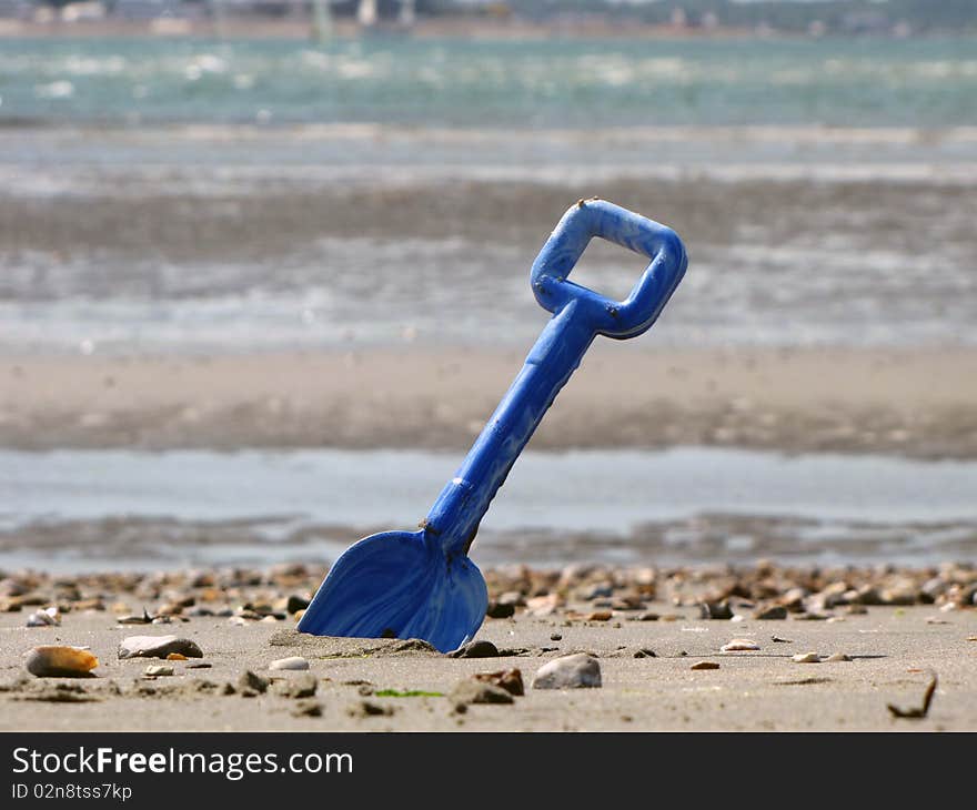 Blue shovel in the sea sand