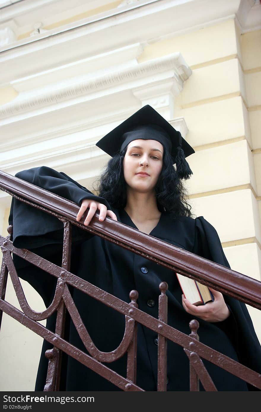 Young student in gown near the university