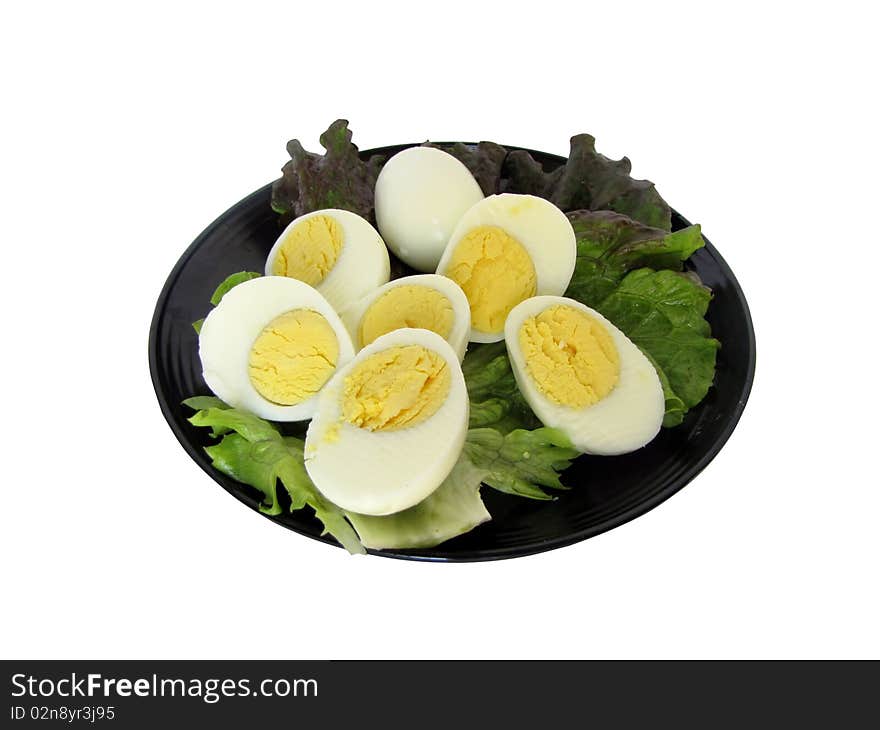 Sliced hard boiled eggs on a leaf of lettuce.