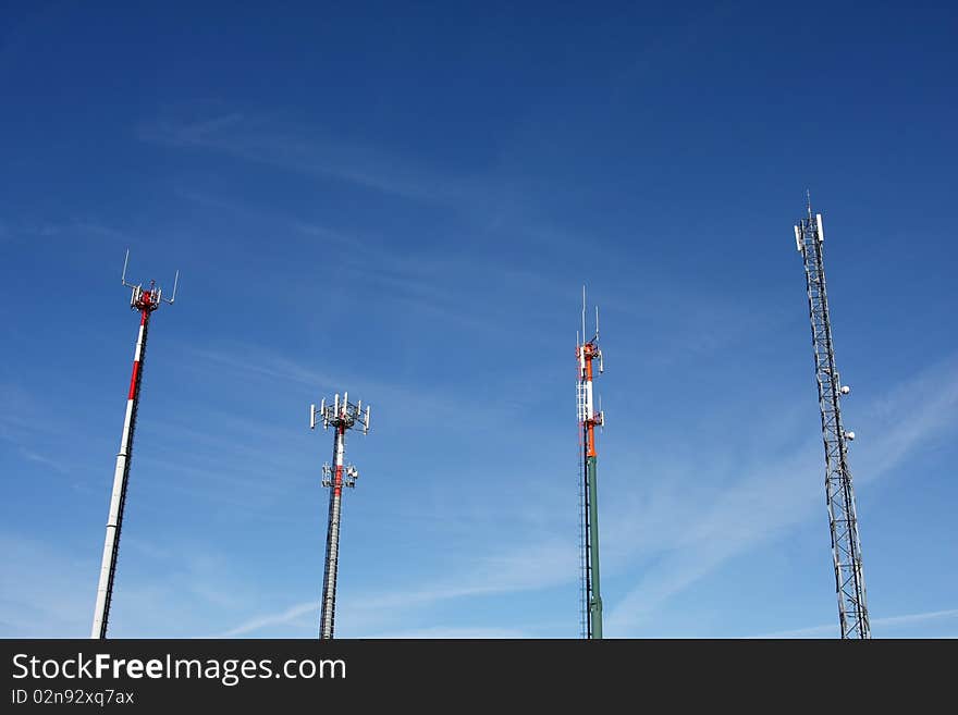 Red and white tower of communications with with a lot of different antennas under clear sky.