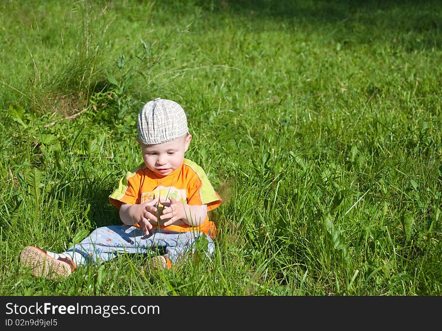 Beautiful little boy looks in green  meadow