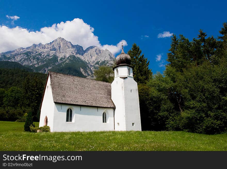 Small white church underneath the alpine peaks. Small white church underneath the alpine peaks