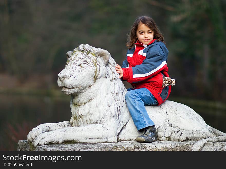 Young Girl Riding On Back Of Stone Lion