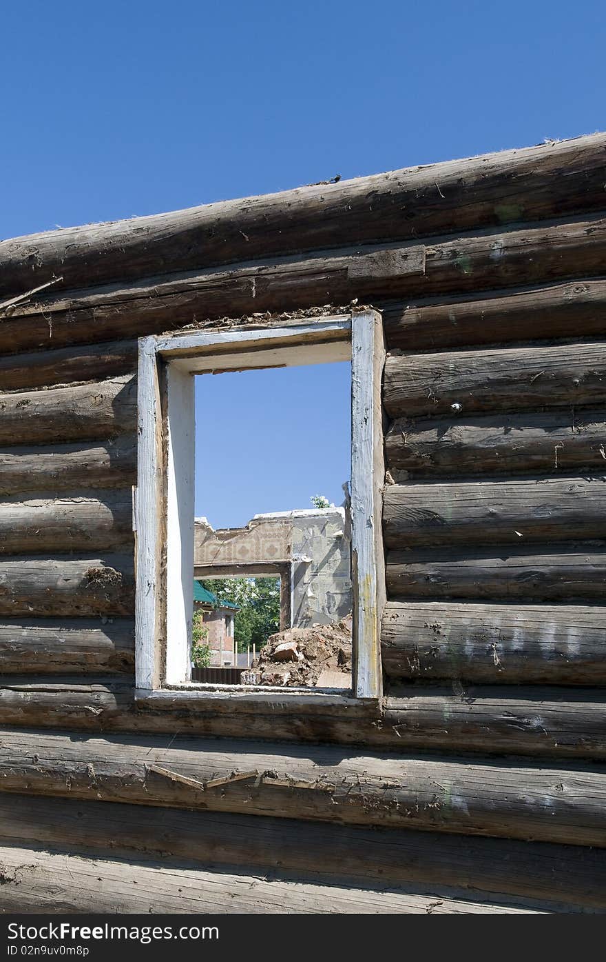 Wall of the wooden destroyed house with a window aperture.