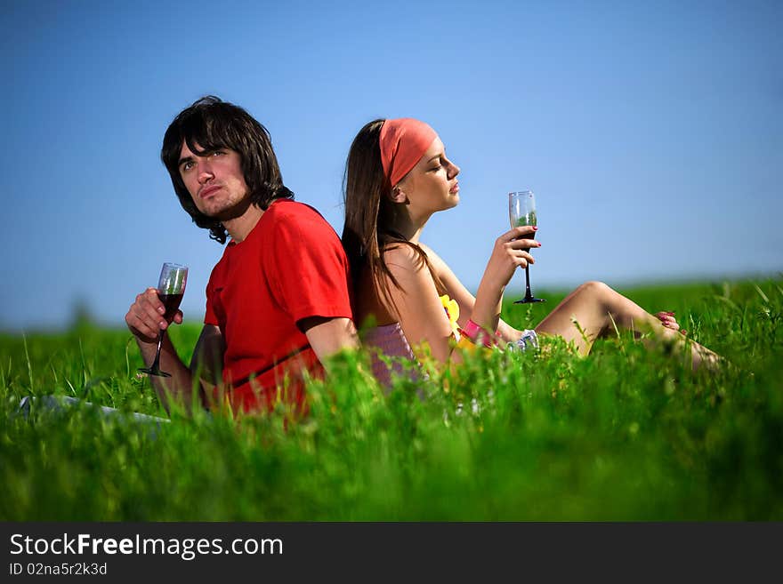 Nice girl and boy with wineglasses on grass