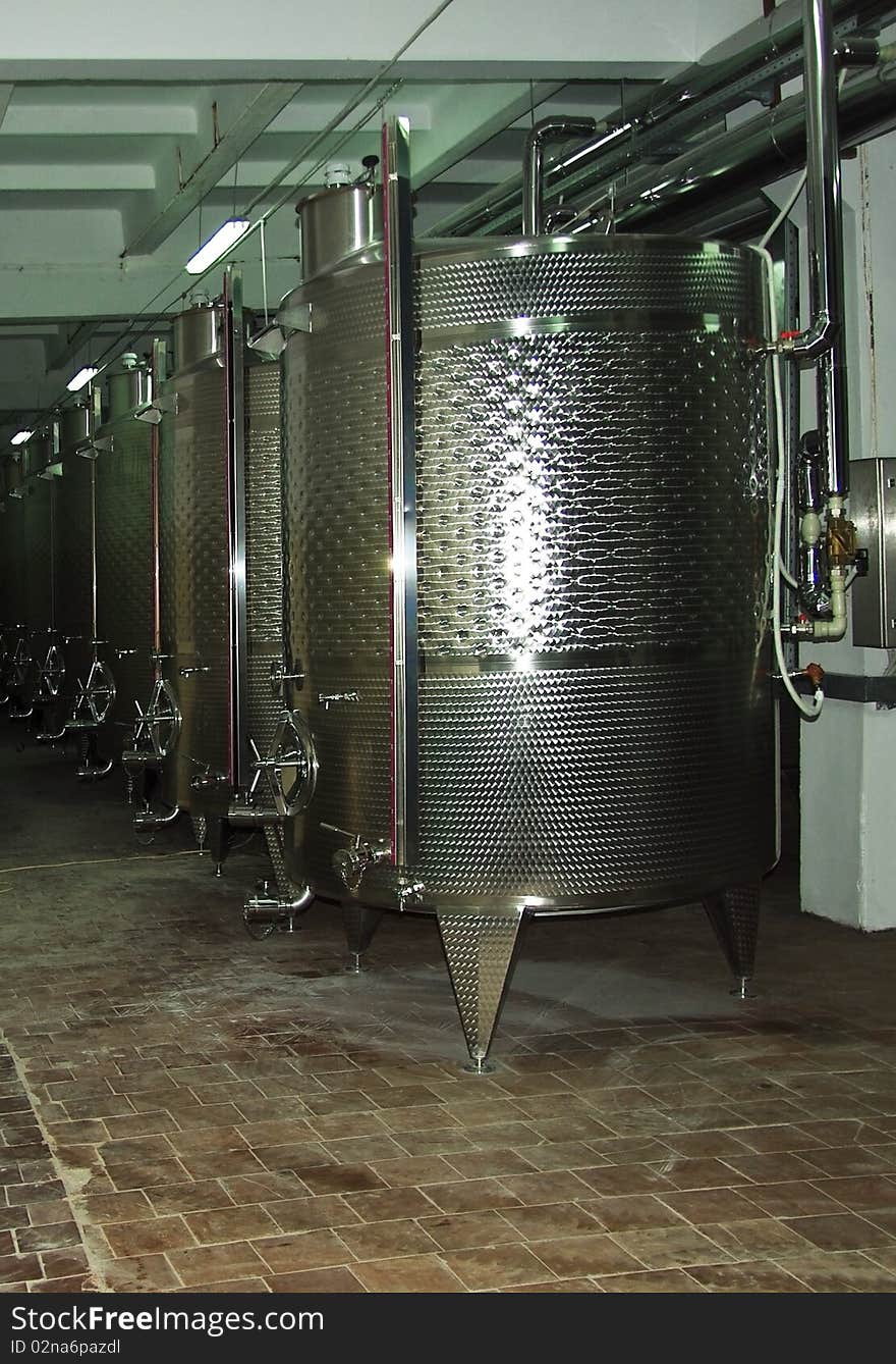 Wine factory - metal barrel of wine. Wine Fermenting in huge vats in a wine cellar.