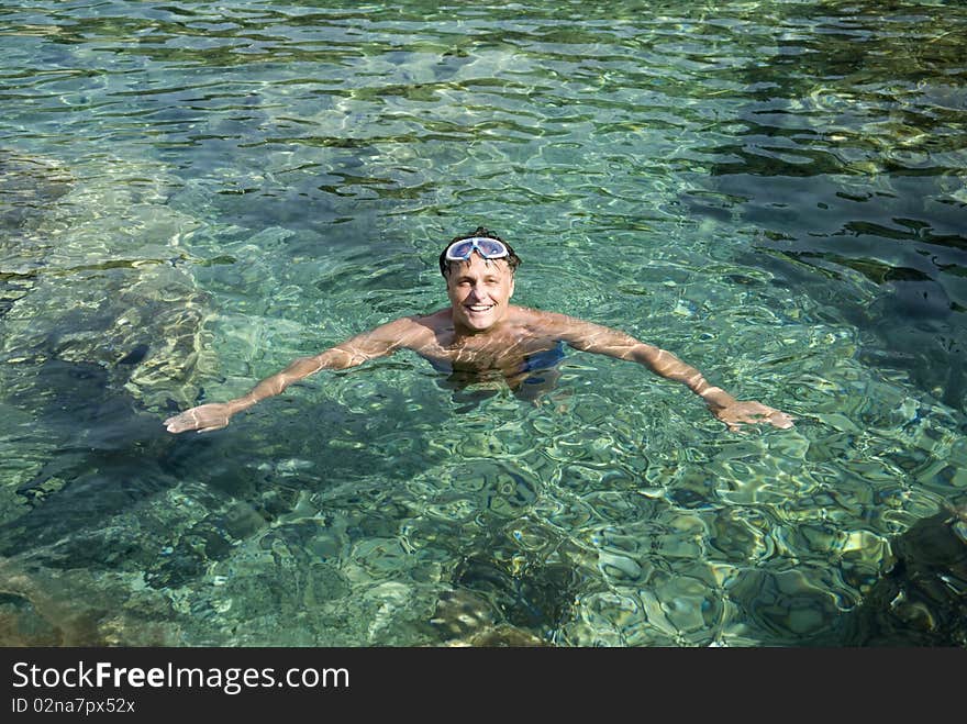 A color portrait photo of a happy smiling forties man relaxing in the clear blue water during his summer vacation. A color portrait photo of a happy smiling forties man relaxing in the clear blue water during his summer vacation.