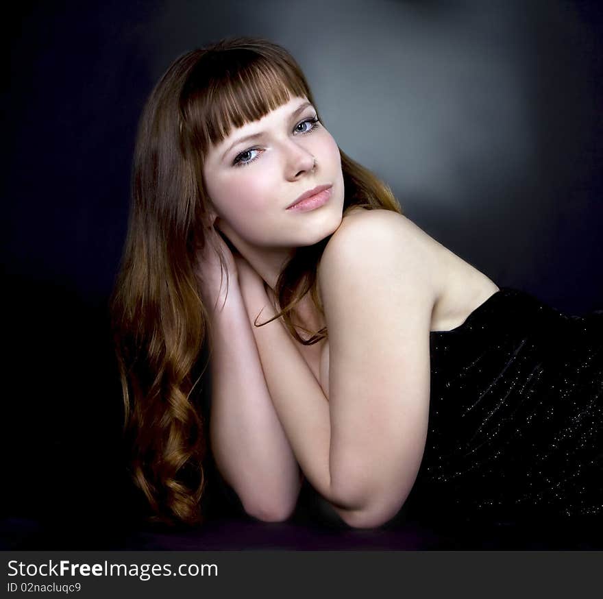 Beautiful brunette girl posing in studio on dark background